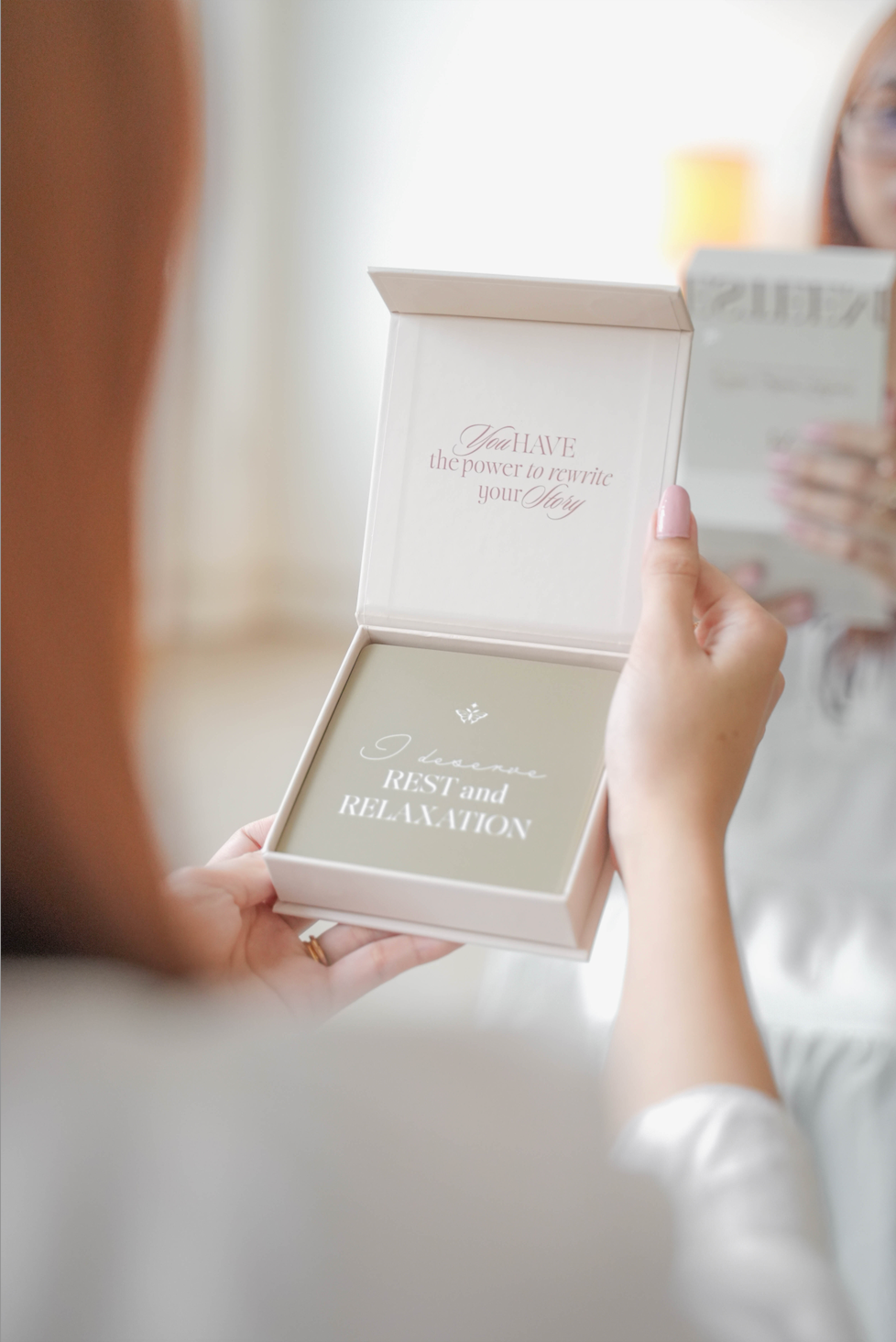 Person holding a box with 'REST and RELAXATION' affirmation card text, blurred background by Esteem Affirmations