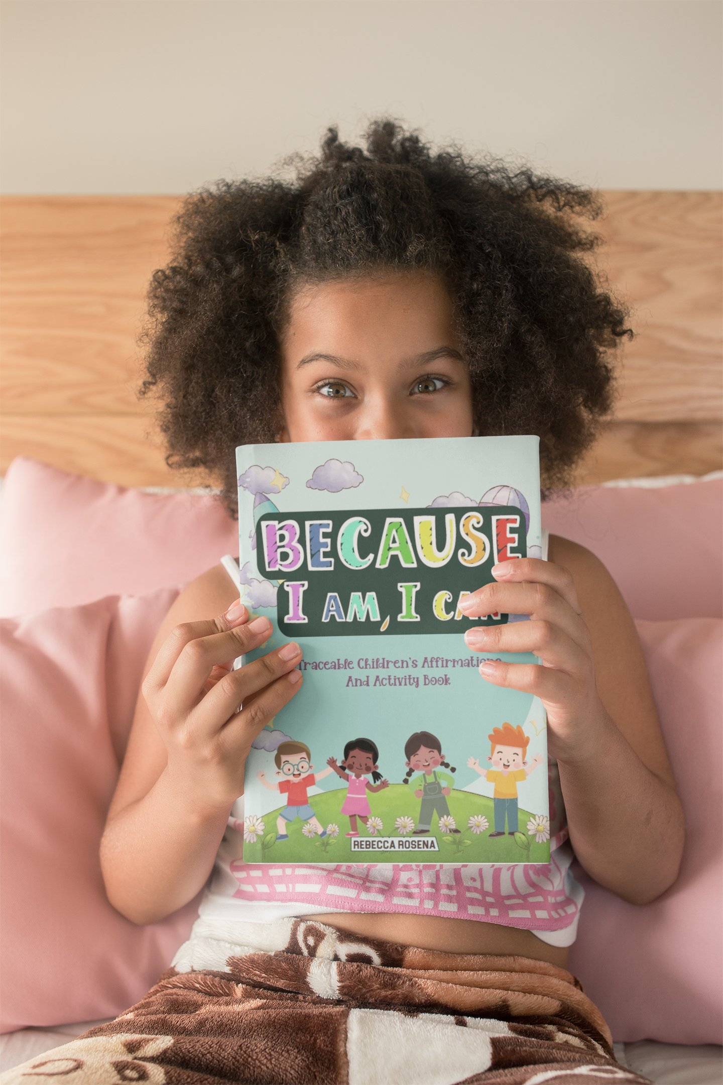 Young child holding "Because I Am, I Can" affirmation book 